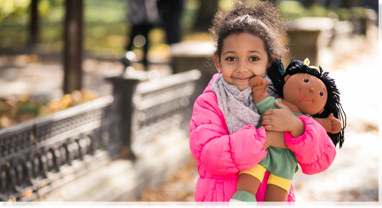 Niña sonriendo con su muñeca